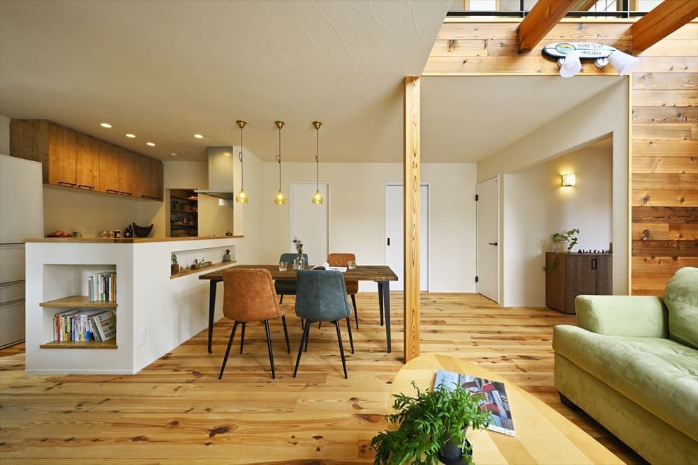 白い造作カウンターのオープンキッチンと無垢材の床が美しいダイニング